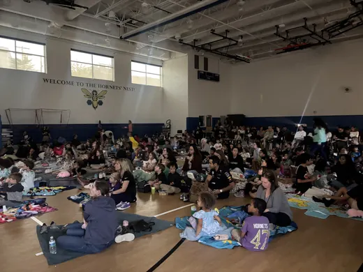 Families on blankets in the gym for movie night
