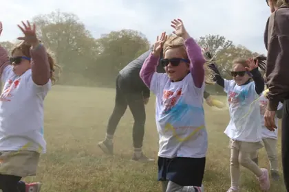 Arms up through a cloud of colour powder